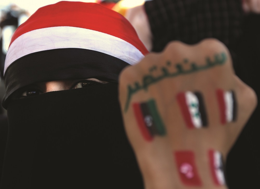A Yemeni fully veiled youth, shows her fist sporting paints of flags of Arab countries which took part in what is known to be the “Arab Spring” and a slogan that reads: “We will win,” during a protest in Sanaa, October 26. AFP / Marwan Naamani